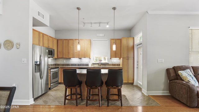 kitchen featuring decorative light fixtures, tasteful backsplash, a breakfast bar area, a center island, and stainless steel appliances