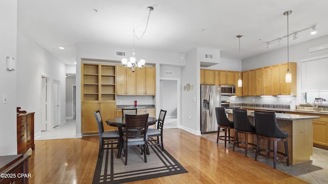 dining room with an inviting chandelier, sink, light hardwood / wood-style floors, and rail lighting