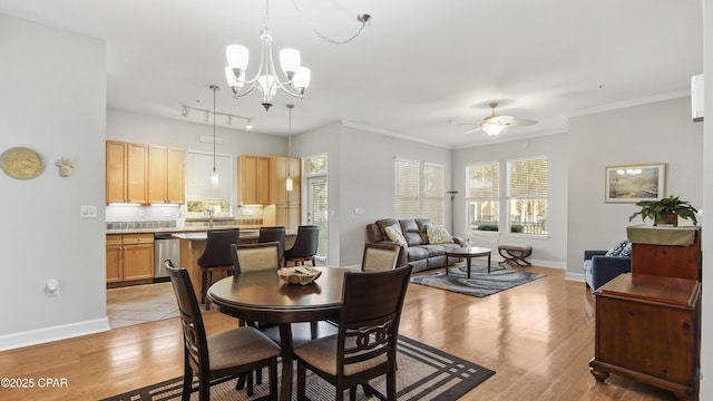 dining room featuring ornamental molding, ceiling fan with notable chandelier, light hardwood / wood-style flooring, and a wealth of natural light