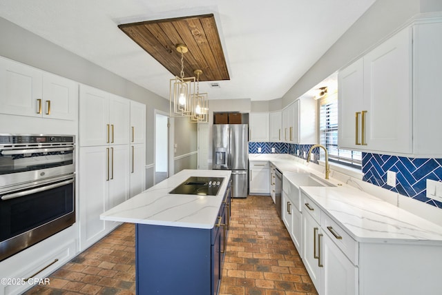 kitchen with appliances with stainless steel finishes, a center island, pendant lighting, and white cabinets