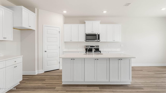 kitchen with an island with sink, appliances with stainless steel finishes, sink, and white cabinets