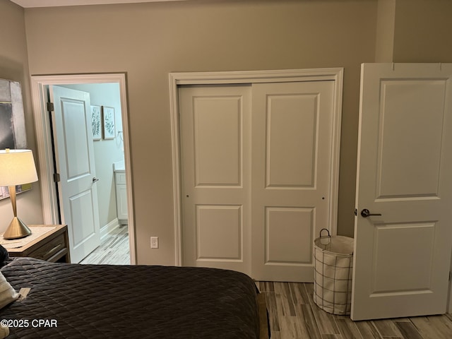 bedroom featuring connected bathroom, light hardwood / wood-style flooring, and a closet