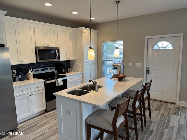 kitchen featuring white cabinetry, appliances with stainless steel finishes, sink, and decorative light fixtures