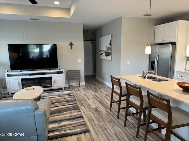 living room with wood-type flooring, a barn door, sink, and ceiling fan