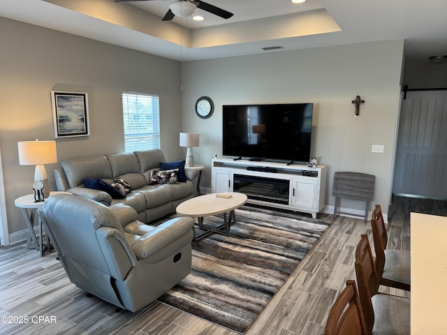 living room with a tray ceiling and ceiling fan