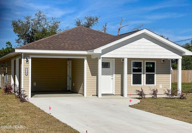 view of front of property with a front lawn, concrete driveway, and roof with shingles