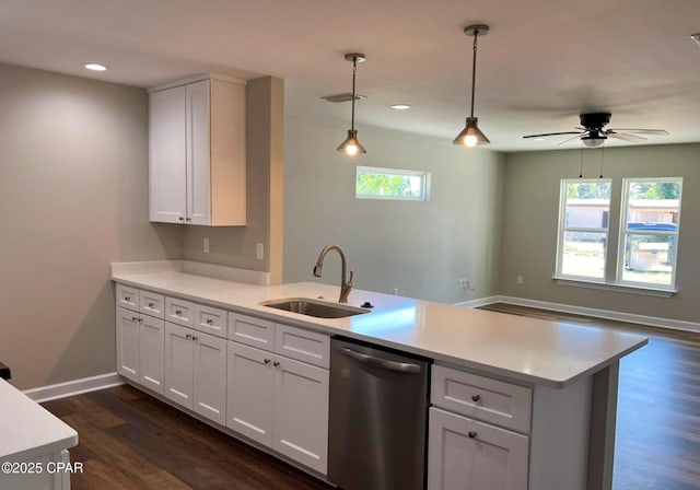 kitchen featuring dark wood-style floors, a peninsula, light countertops, stainless steel dishwasher, and a sink