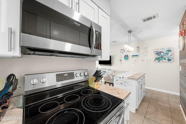 kitchen featuring pendant lighting, white cabinets, light tile patterned floors, stainless steel appliances, and a textured ceiling