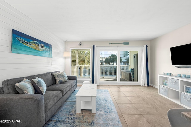 living room featuring light tile patterned flooring and wooden walls