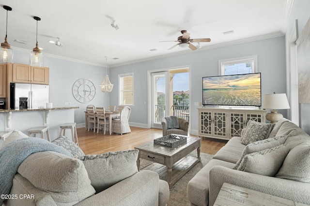 living area with ornamental molding, light wood-type flooring, baseboards, and a ceiling fan