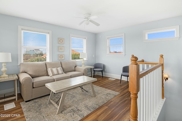 living area with dark wood-style floors, visible vents, baseboards, and a ceiling fan