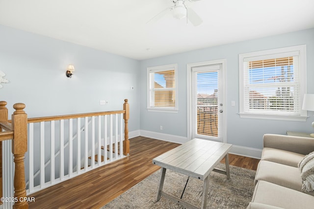 living room featuring ceiling fan, baseboards, and dark wood-style flooring