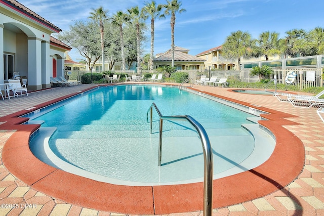 pool with a community hot tub, a patio, and fence