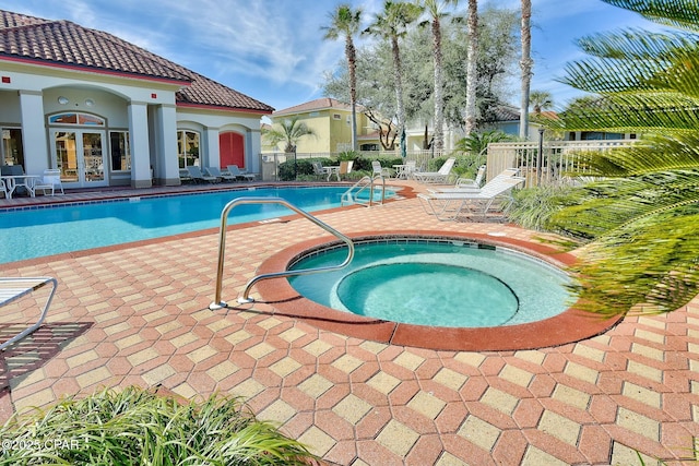 community pool with french doors, fence, a hot tub, and a patio