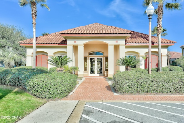 mediterranean / spanish home with stucco siding, a tile roof, and french doors