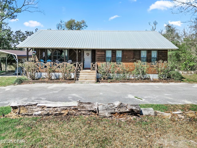 view of front of house with a carport, a porch, metal roof, and driveway