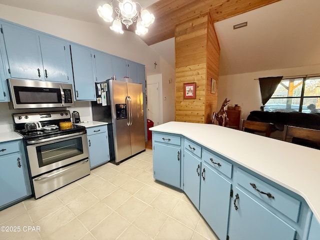 kitchen featuring light countertops, vaulted ceiling, appliances with stainless steel finishes, an inviting chandelier, and blue cabinets