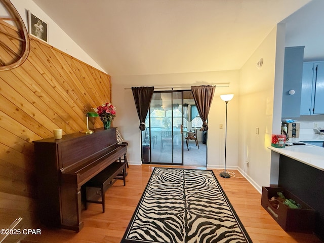 sitting room with lofted ceiling, light wood-style floors, and wood walls