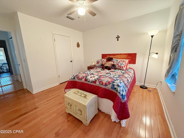 bedroom with light wood finished floors, visible vents, a ceiling fan, and baseboards