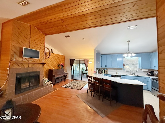 kitchen with blue cabinets, sink, a kitchen bar, hanging light fixtures, and stainless steel appliances