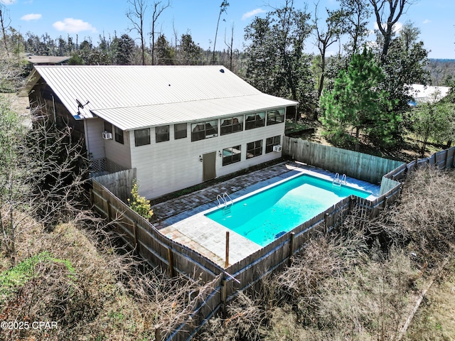 rear view of house featuring a patio area, a fenced in pool, metal roof, and a fenced backyard