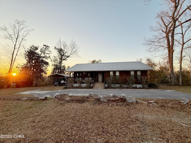 view of front of home with a detached carport, covered porch, driveway, and metal roof