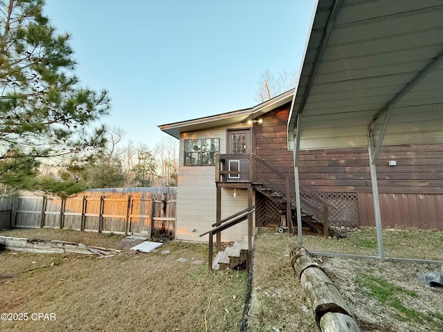 view of side of property featuring stairs and fence