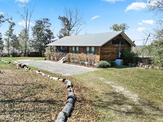 view of side of property with a yard, central AC unit, driveway, and metal roof