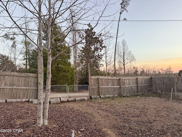 yard at dusk with a fenced backyard