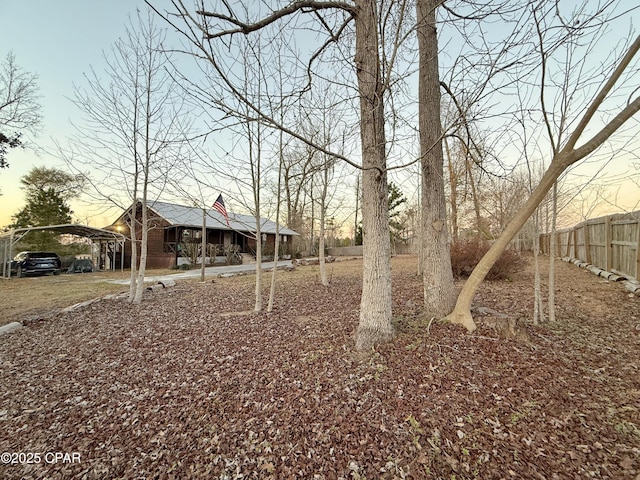 yard at dusk with a carport and fence