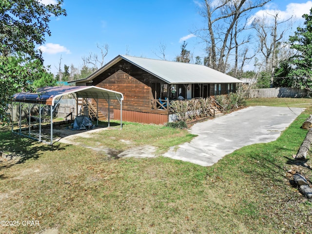 exterior space with a detached carport, fence, a front yard, metal roof, and driveway