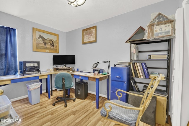 home office with a textured ceiling and light wood-type flooring