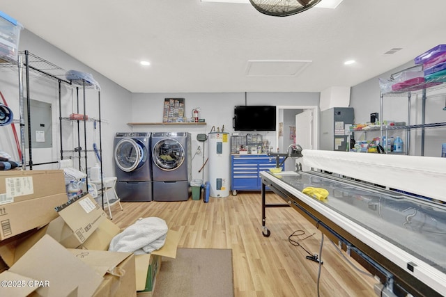 laundry area featuring separate washer and dryer, light hardwood / wood-style floors, water heater, and a textured ceiling