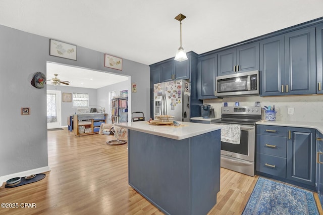 kitchen with hanging light fixtures, stainless steel appliances, a center island, blue cabinets, and light wood-type flooring