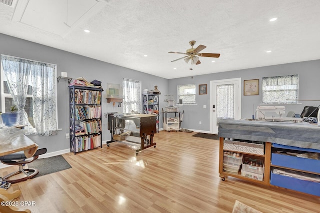 interior space featuring ceiling fan, a textured ceiling, and light hardwood / wood-style flooring