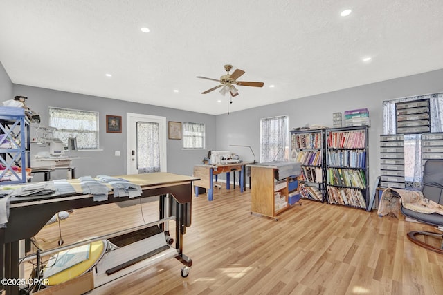 home office with a healthy amount of sunlight, light hardwood / wood-style flooring, and a textured ceiling