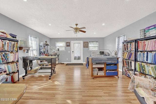 interior space featuring ceiling fan, light hardwood / wood-style floors, and a textured ceiling