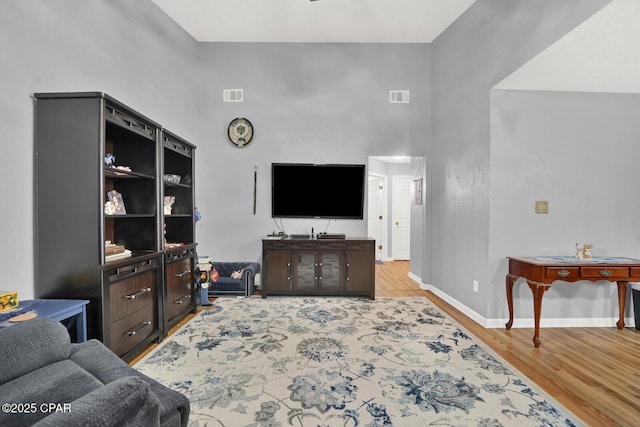 living room with a towering ceiling and light hardwood / wood-style floors