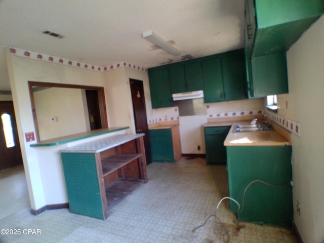 kitchen featuring kitchen peninsula, sink, and green cabinets