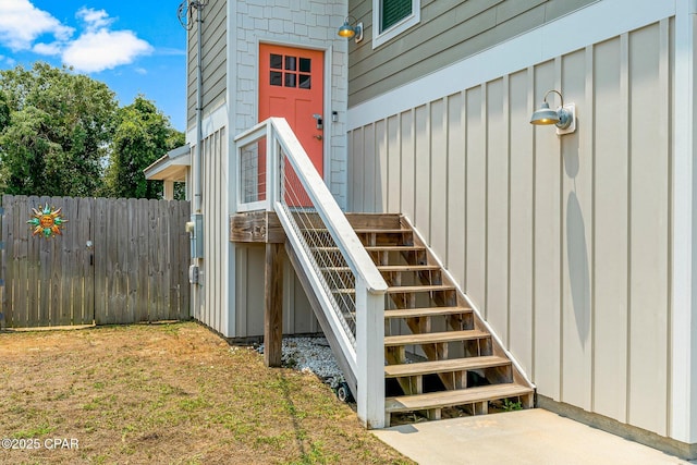 entrance to property featuring board and batten siding and fence