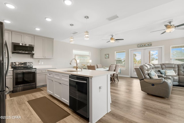 kitchen with a center island with sink, light countertops, visible vents, appliances with stainless steel finishes, and a sink