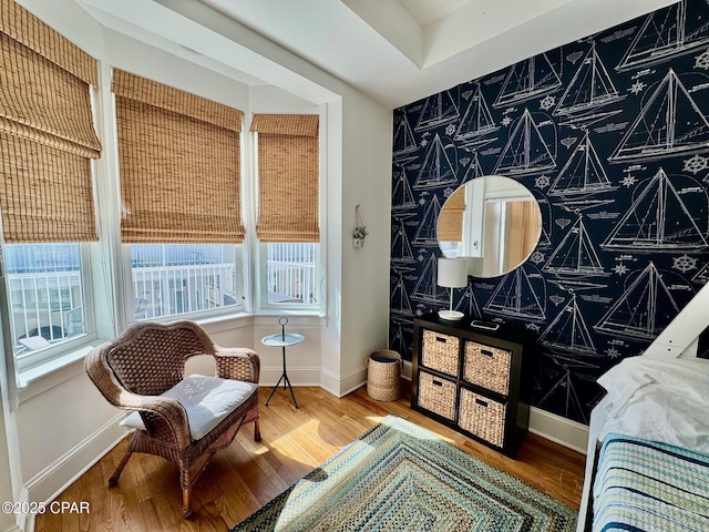 interior space with baseboards, wood finished floors, an accent wall, and wallpapered walls