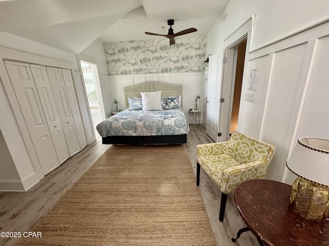 bedroom featuring wallpapered walls, a decorative wall, wood finished floors, and wainscoting