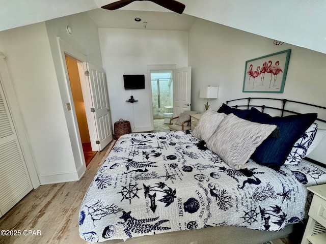 bedroom with high vaulted ceiling, a ceiling fan, ensuite bath, wood finished floors, and baseboards