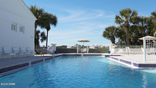 pool with a patio area and fence