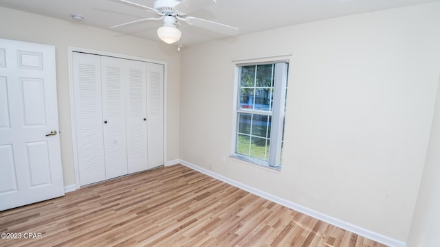 unfurnished bedroom featuring multiple windows, a closet, light wood-type flooring, and baseboards