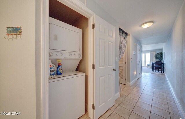 washroom featuring stacked washer and dryer and light tile patterned flooring