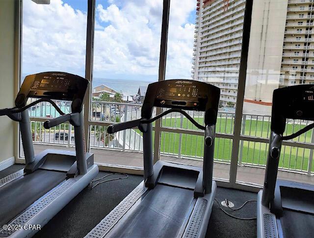 workout area featuring floor to ceiling windows and a water view