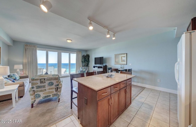 kitchen featuring light tile patterned floors, a breakfast bar, track lighting, a kitchen island, and white fridge