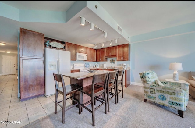 kitchen featuring light tile patterned floors, white appliances, and a center island